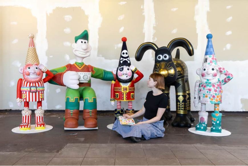 Woman sitting next to 5 wallace and gromit sculptures